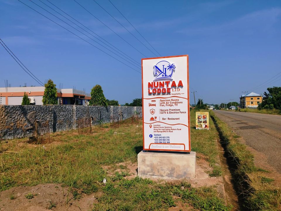 Nuntaa Lodge signboard beside the road, with the boundary wall behind it